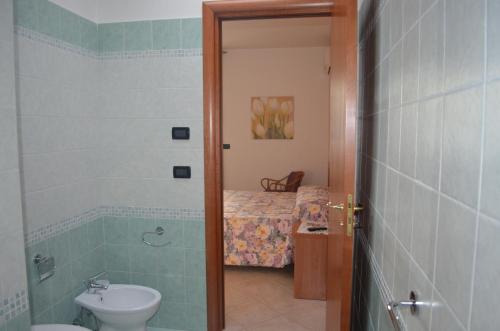 een badkamer met een wastafel, een toilet en een bed bij B&B Marina in Castro di Lecce