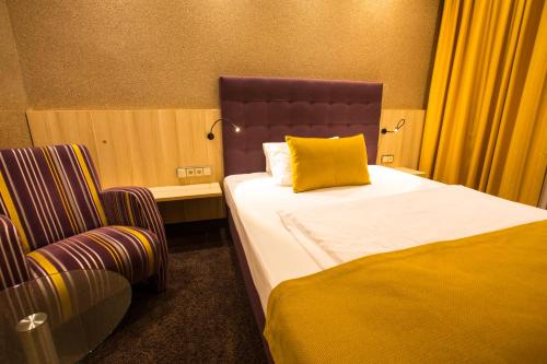 a bedroom with a bed with a yellow pillow and a chair at Top Hotel Hammer - Mainz Hauptbahnhof in Mainz