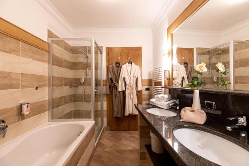a bathroom with two sinks and a tub and a shower at Aktiv & Wellnesshotel Zentral in Prato allo Stelvio