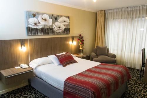 a hotel room with a bed and a chair at Hotel Don Eduardo in Temuco