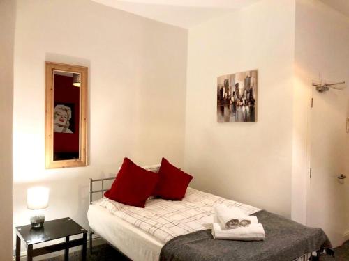 um quarto com uma cama com almofadas vermelhas e um espelho em BELMONT Apartments em Liverpool