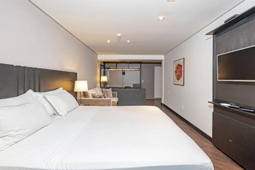 a bedroom with a large white bed with a flat screen tv at Slaviero Baia Norte Florianópolis in Florianópolis