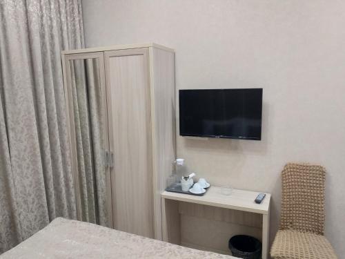 a hotel room with a desk and a television on the wall at Hotel Grin in Moscow