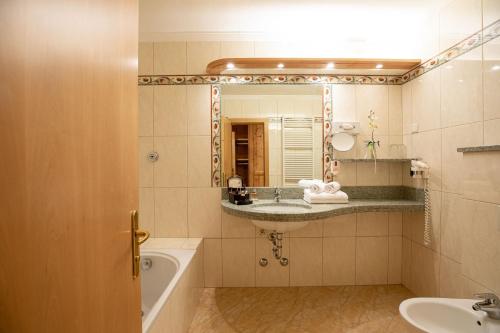 a bathroom with a sink and a tub and a mirror at Aktiv & Wellnesshotel Zentral in Prato allo Stelvio