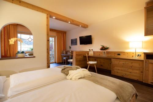 a bedroom with a large bed and a desk at Aktiv & Wellnesshotel Zentral in Prato allo Stelvio