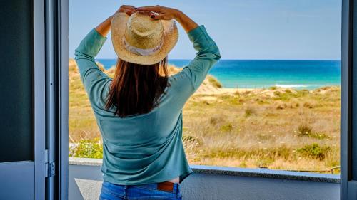 a woman wearing a straw hat looking at the ocean at Casa Reyes El Palmar in El Palmar