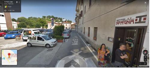 a woman standing in front of a building with a car at Hotel Spagna in Arona