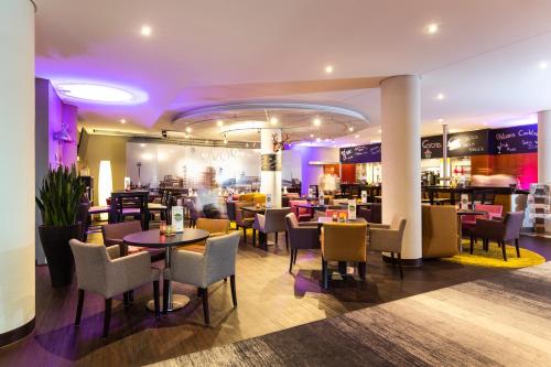 a restaurant with tables and chairs and a bar at Novotel Düsseldorf City West in Düsseldorf