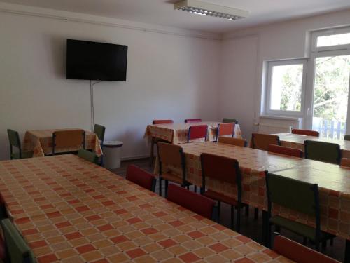 a room with tables and chairs and a flat screen tv at Tihany Község Önkormányzat - Ifjúsági Szállás in Tihany
