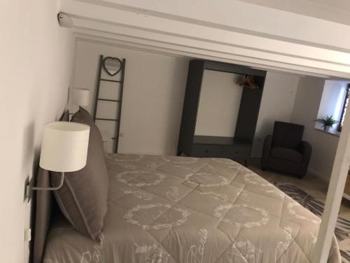 a bedroom with a bed with a lamp and a chair at A Casa di Vale in Siracusa