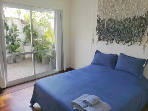 a bedroom with a blue bed and a large window at Dos Patios - Luz, tranquilidad y verde in La Plata