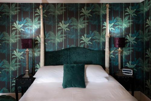 a bedroom with a bed with a green headboard and wallpaper at The White House in Hastings