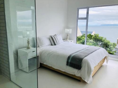 a white bedroom with a bed and a large window at Seascape in De Kelders