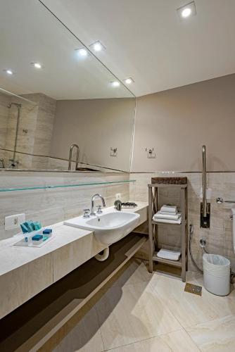 a bathroom with a sink and a swimming pool at Slaviero Baia Norte Florianópolis in Florianópolis