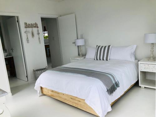 a white bedroom with a large bed with white sheets at Seascape in De Kelders