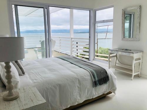 a bedroom with a bed and a desk and windows at Seascape in De Kelders