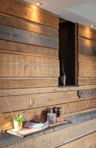 a wooden wall with a shelf with magazines and a plant at K & N Appartement à 1 km du circuit in Francorchamps