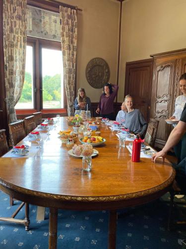 Un grupo de personas sentadas alrededor de una gran mesa de madera. en Château Le Boisrenault, en Buzançais