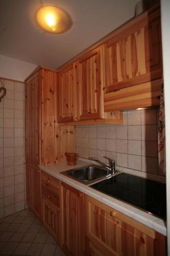 a kitchen with wooden cabinets and a sink at Residence Valfassa in Canazei