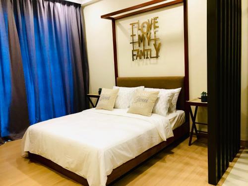 a bedroom with a large white bed with blue curtains at Studio1111@TimurBay in Kuantan
