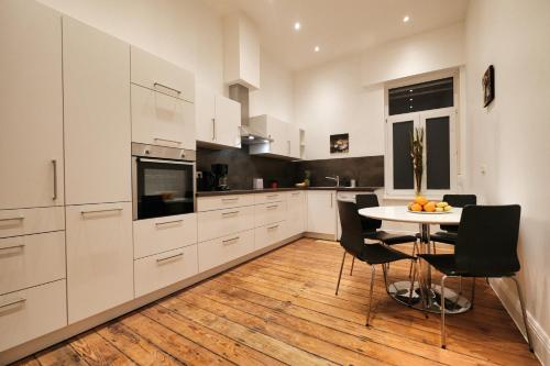 une cuisine avec des placards blancs et une table avec des chaises dans l'établissement Appartement Deluxe, à Worms