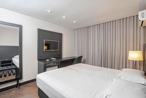 a hotel room with a bed and a television at Slaviero Baia Norte Florianópolis in Florianópolis