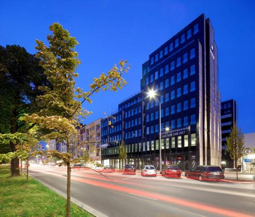 a city street with cars driving past a tall building at Space Apartments Szczecin in Szczecin