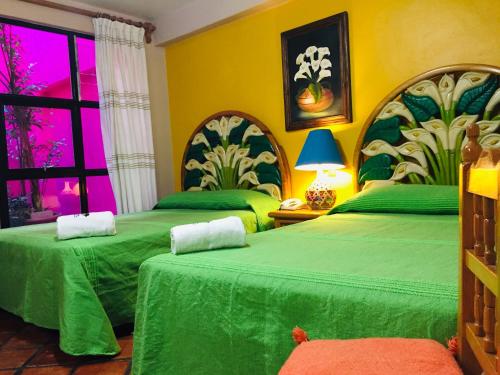 a bedroom with two green beds and a window at Hotel Cazomalli Oaxaca in Oaxaca City