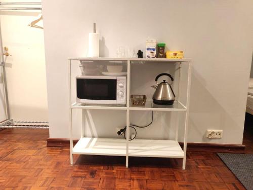 a white shelf with a microwave and a tea kettle at Studio apartment VICTORIA in Helsinki city center in Helsinki