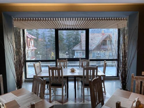 a dining room with a table and chairs and a large window at Roberto Hotel in Sinaia