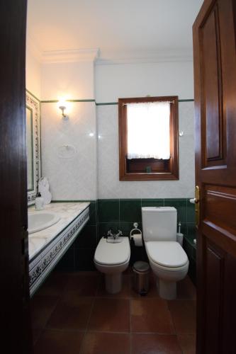 a bathroom with a toilet and a sink and a window at Villa Altos de Santiago in Playa de Santiago