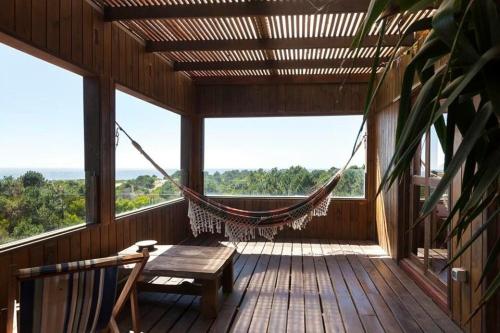 a hammock on a screened in porch with a swing at Eco House Via Verde in Punta Del Diablo