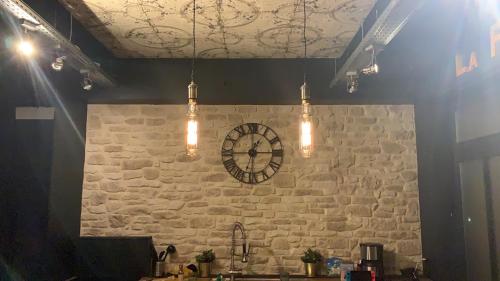 eine Steinmauer mit einer Uhr an einer Wand mit Licht in der Unterkunft La Fabrique à Souvenirs in Saint-Malo