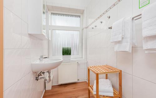 a white bathroom with a sink and a window at Hotel Rutherbach in Essen