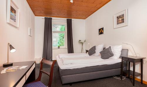 a bedroom with a bed and a desk and a window at Hotel Rutherbach in Essen