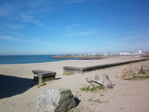 a bench on a beach with rocks and the ocean at Kerstunt Chambre d'hôtes Relais Motards in Guérande