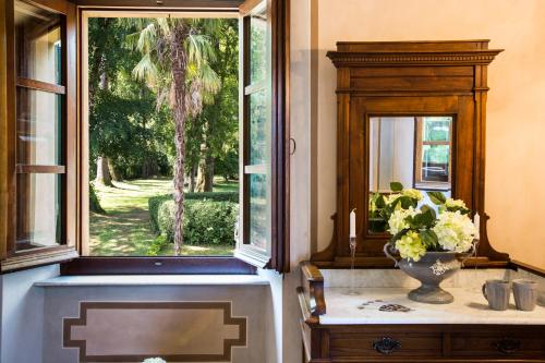 un baño con una ventana y un jarrón de flores sobre una mesa en VILLA TURRI - Luxury Country & Padel Resort en Camporgiano