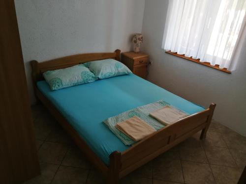 a bed with blue sheets and pillows in a bedroom at Apartmani Emily in Jezera