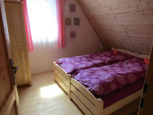 1 dormitorio con cama morada en el ático en Rekreační dům v Brdech Pod Svatou Annou, en Ohrazenice