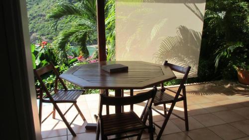 a wooden table and chairs on a patio with a view at Anse Figuier Gites de France in Terre-de-Haut