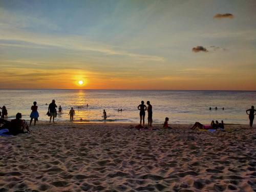 a group of people on the beach at sunset at PHADEE APARTMENT in Karon Beach