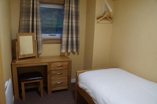 a bedroom with a bed and a dresser and a window at Myrtle Bank Hotel in Gairloch