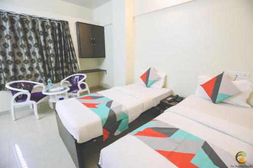 a room with two beds and a table and chairs at The Paradise Aundh in Pune