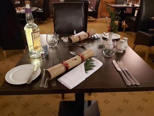 a table with plates and napkins and a bottle of wine at The Rowan Tree Country Hotel in Aviemore