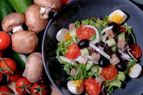 a bowl of salad with tomatoes and other vegetables at Hotel Ambassador Zermatt in Zermatt