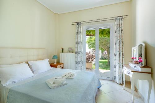 een witte slaapkamer met een bed en een glazen schuifdeur bij Rania Apartments Helmata in Khelmáta