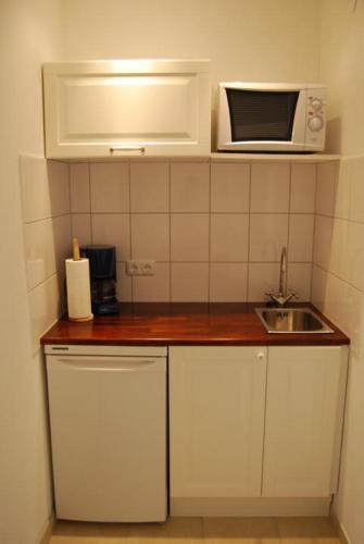 a small kitchen with a sink and a microwave at Wohlfühlhotel Hörn van Diek Garni mit Schwimmbad in Bensersiel