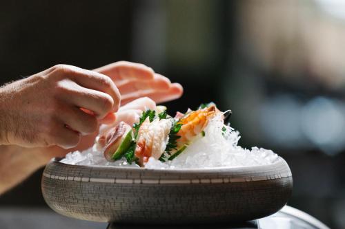 a person holding a plate of rice and sushi at Raffl's Tyrol Hotel in Sankt Anton am Arlberg