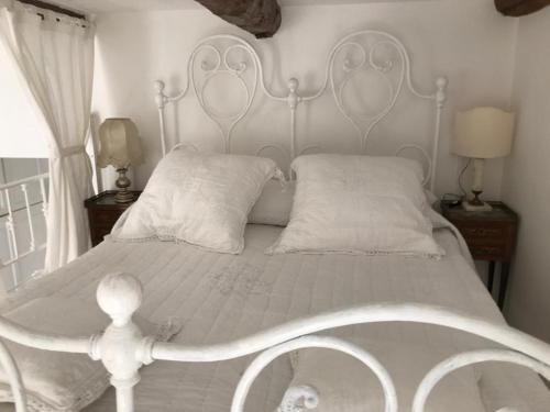 a white bed with a white headboard and two pillows at Maison Menton in Menton