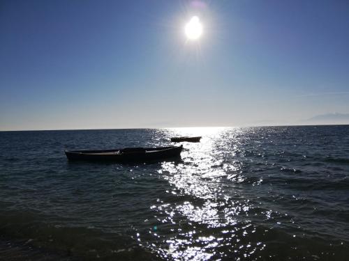 two boats on the water with the sun in the sky at Crystal Blue Apartments in Nea Kalikratia